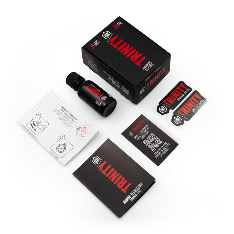 Top-down view of a TRINITY branded product kit, including a black bottle, a black box, two instruction booklets, a warranty card, and two rectangular TRINITY stickers, all arranged neatly on a white surface.