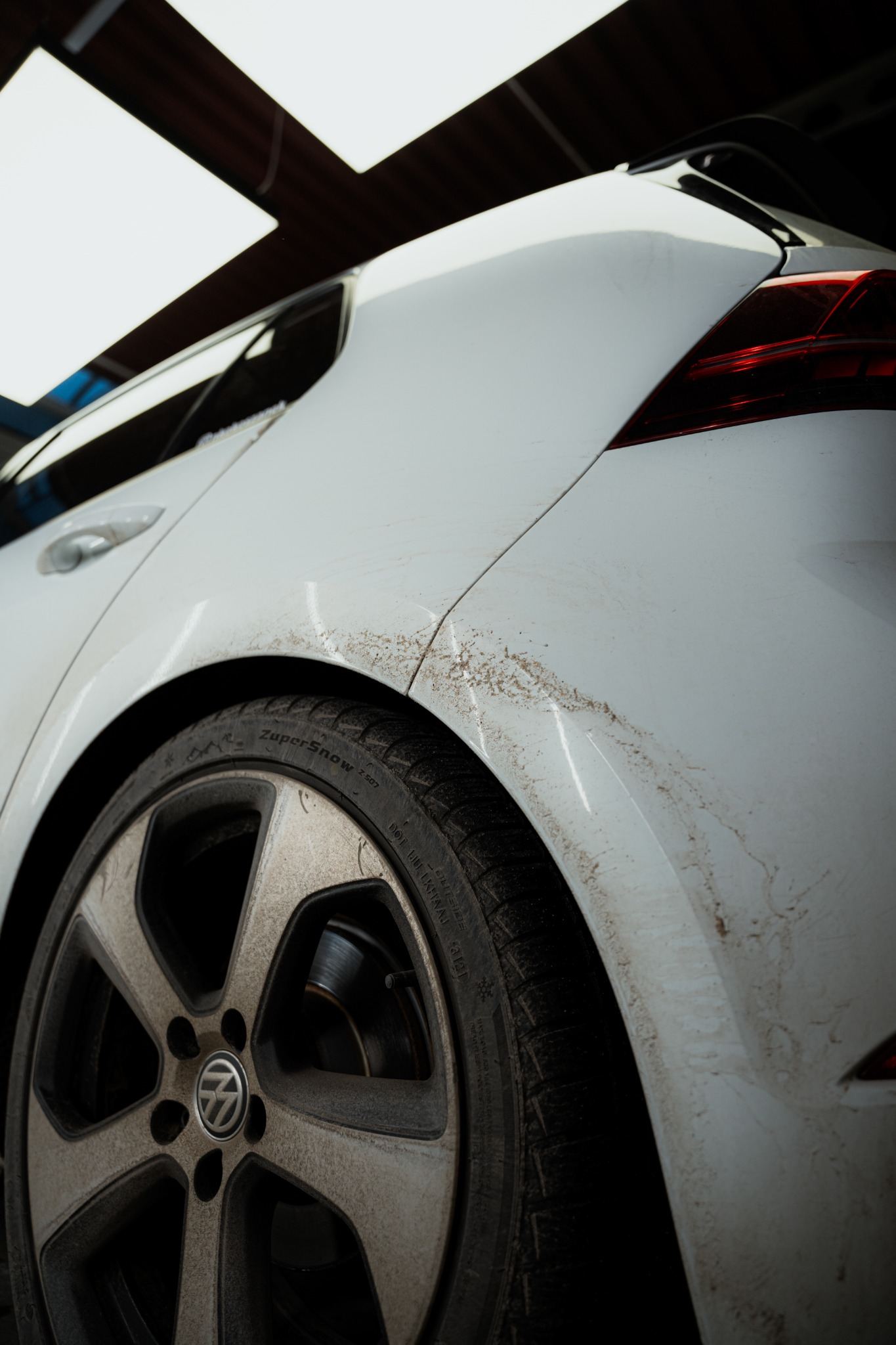 Heavy road grime around a car rear wheel arch and lower body panel