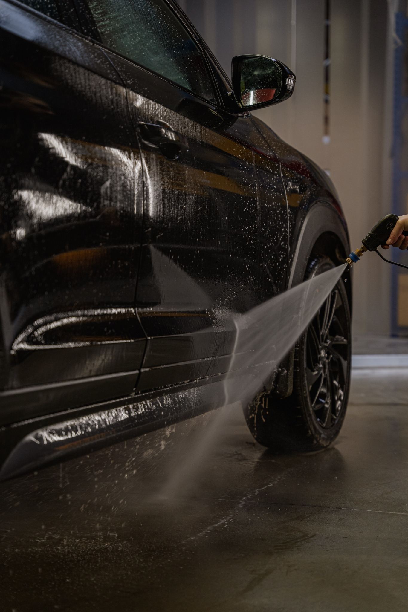 Pressure rinsing loosened traffic film from the lower panels of a car